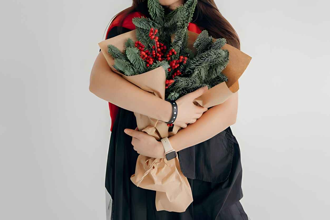 Girl holding a winter bouquet with spruce branches and kraft paper