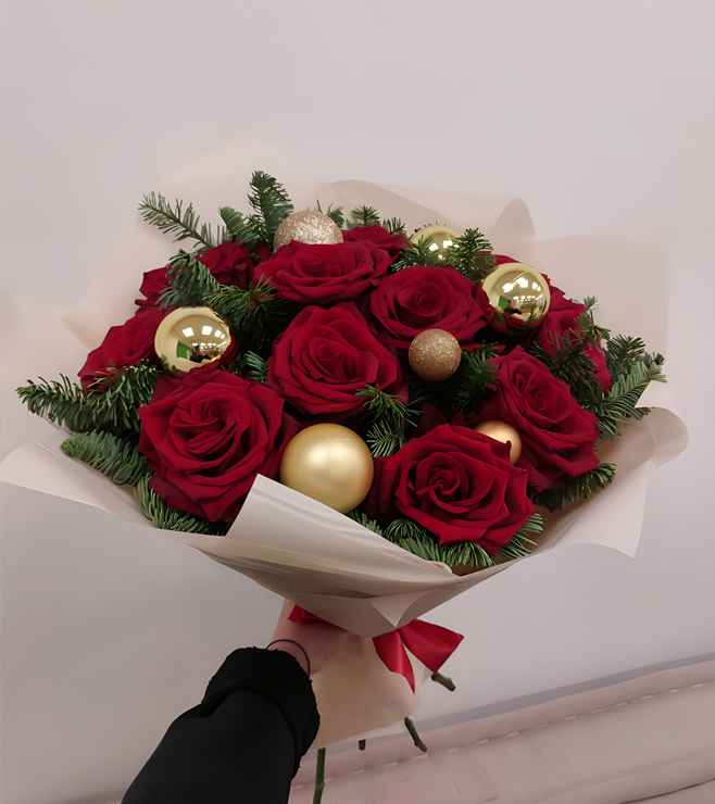 Festive bouquet of red roses with gold ornaments and greenery.